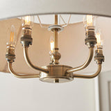 Caldmere 5 Light Pendant in brass, showing five candle bulbs on curved arms with a natural fabric shade above, close-up view.