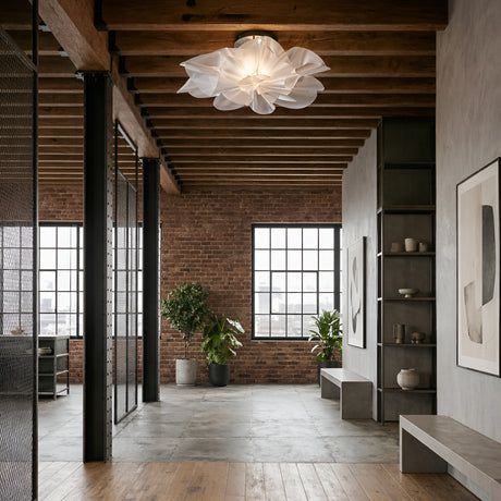 Modern industrial loft with exposed brick walls, grid windows, wood ceiling beams, concrete floor, minimalist furniture, plants, abstract art, and a striking sculptural fixture featuring the Violla LED Flush Ceiling Light - White.