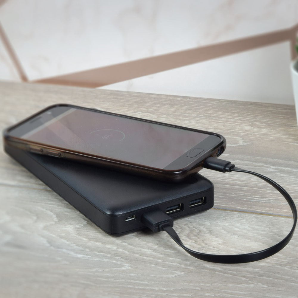AV:Link 20cm USB Type A-C flat sync and charge cable by AVSL connecting a smartphone to a black power bank with dual USB ports on a wooden surface.