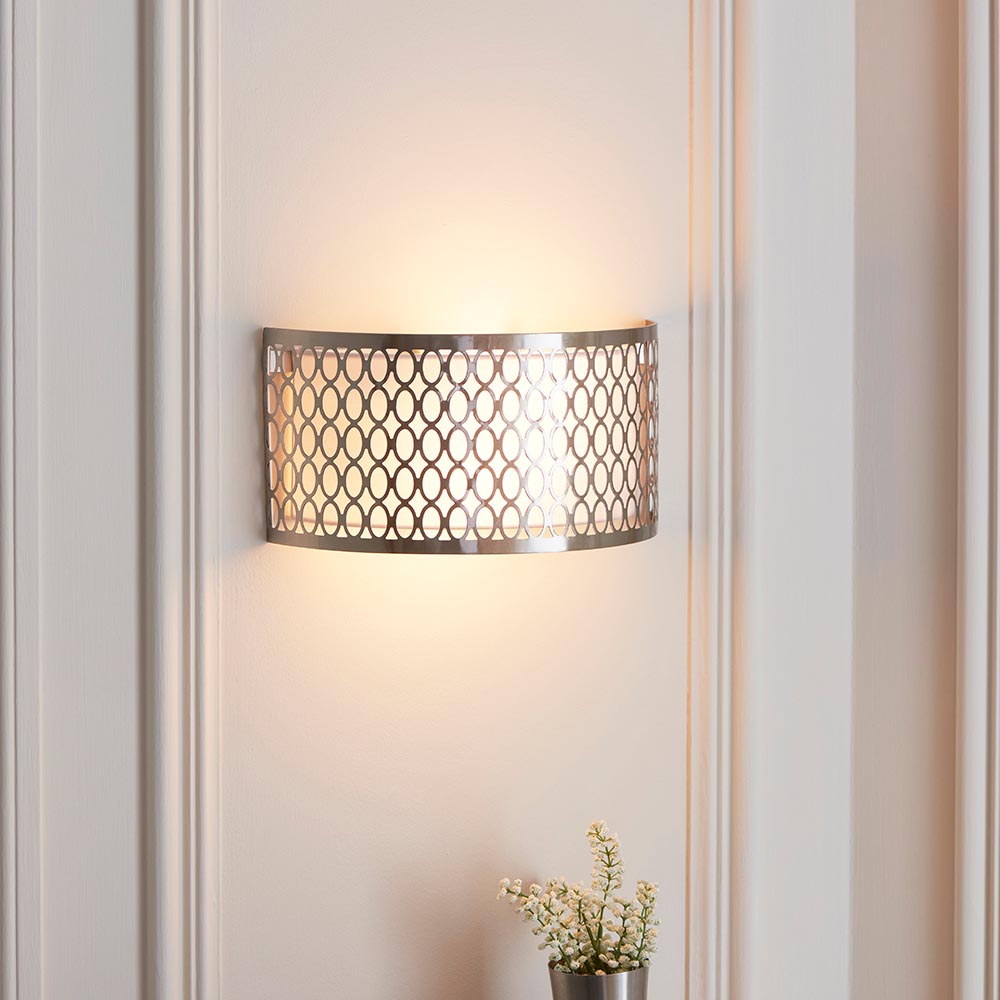 Endon Rosaline 2 Light Wall Light in nickel with geometric fretwork, white fabric inner shade and frosted glass diffusers, lit on a panelled wall.