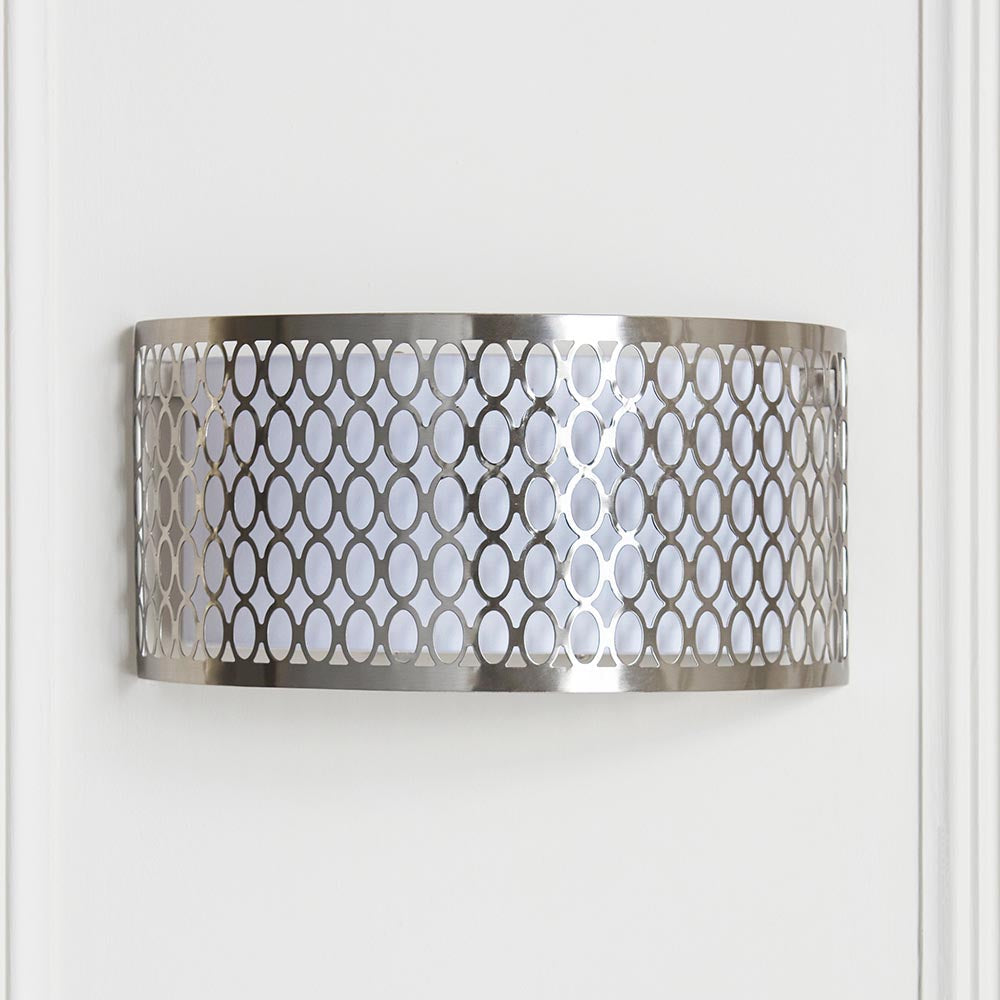 Endon Rosaline 2 light wall light in satin nickel with geometric fretwork outer and white fabric inner shade, mounted on a pale panelled wall.