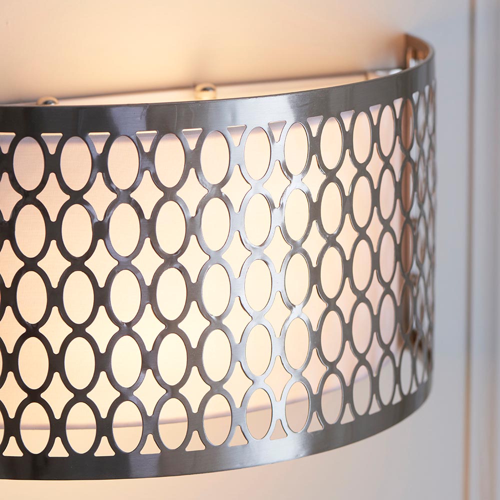 Close-up of Endon Rosaline 2 light wall light in satin nickel with circular geometric fretwork, white fabric inner shade, and curved form against a pale wall.