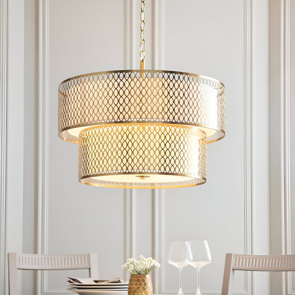 Endon Rosaline 6 light chandelier in gold with two tiered fretwork drums and white inner shade, hanging from a chain above a dining table setting.