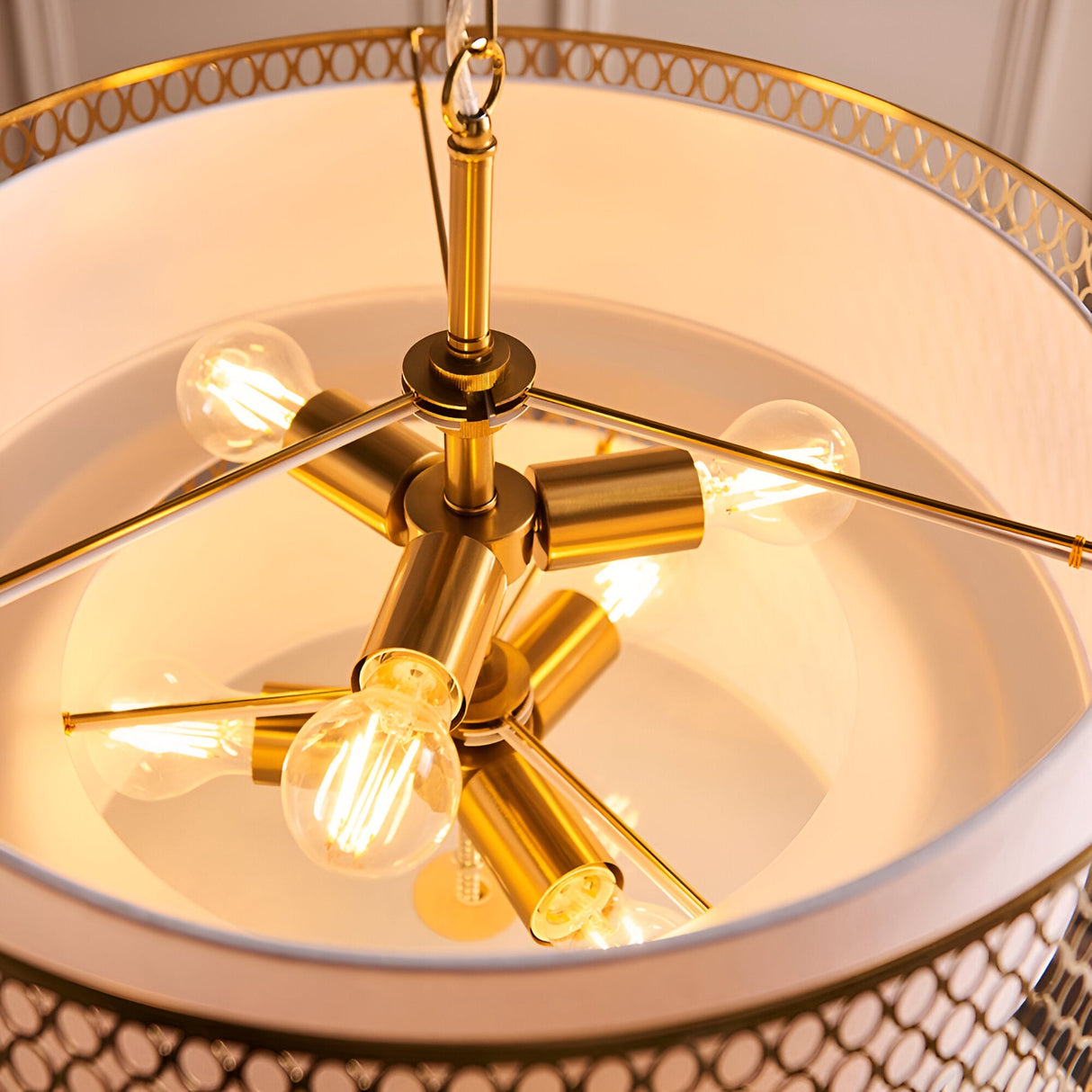 Close-up of Endon Rosaline 6 Light Chandelier in gold, showing six E27 lit bulbs on brass arms within the fretwork drum and white inner shade.
