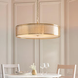 Rosaline 5-Light Pendant in gold and white, a large drum fixture with geometric fretwork shade and frosted glass diffuser, hung above a dining table.
