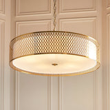 Rosaline 5 Light Pendant in gold and white, large drum shade with geometric fretwork exterior and frosted glass diffuser, hung from a chain in a panelled room.