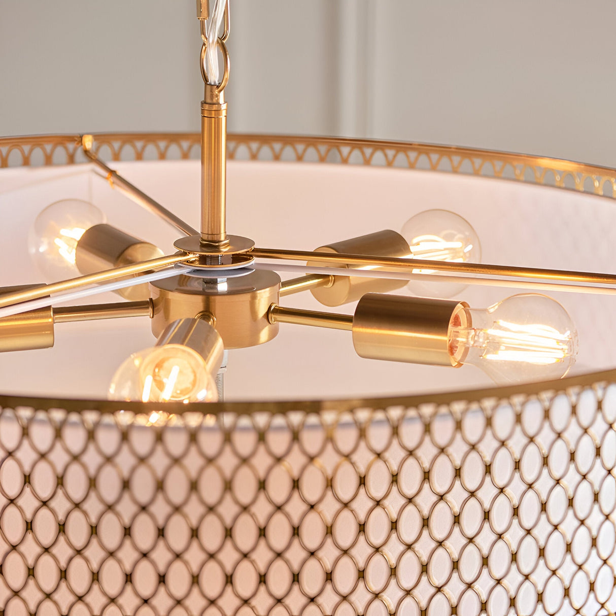 Rosaline 5-light pendant close-up showing gold metal arms with five E27 bulbs beneath a white fabric shade with gold fretwork trim and patterned outer detail.