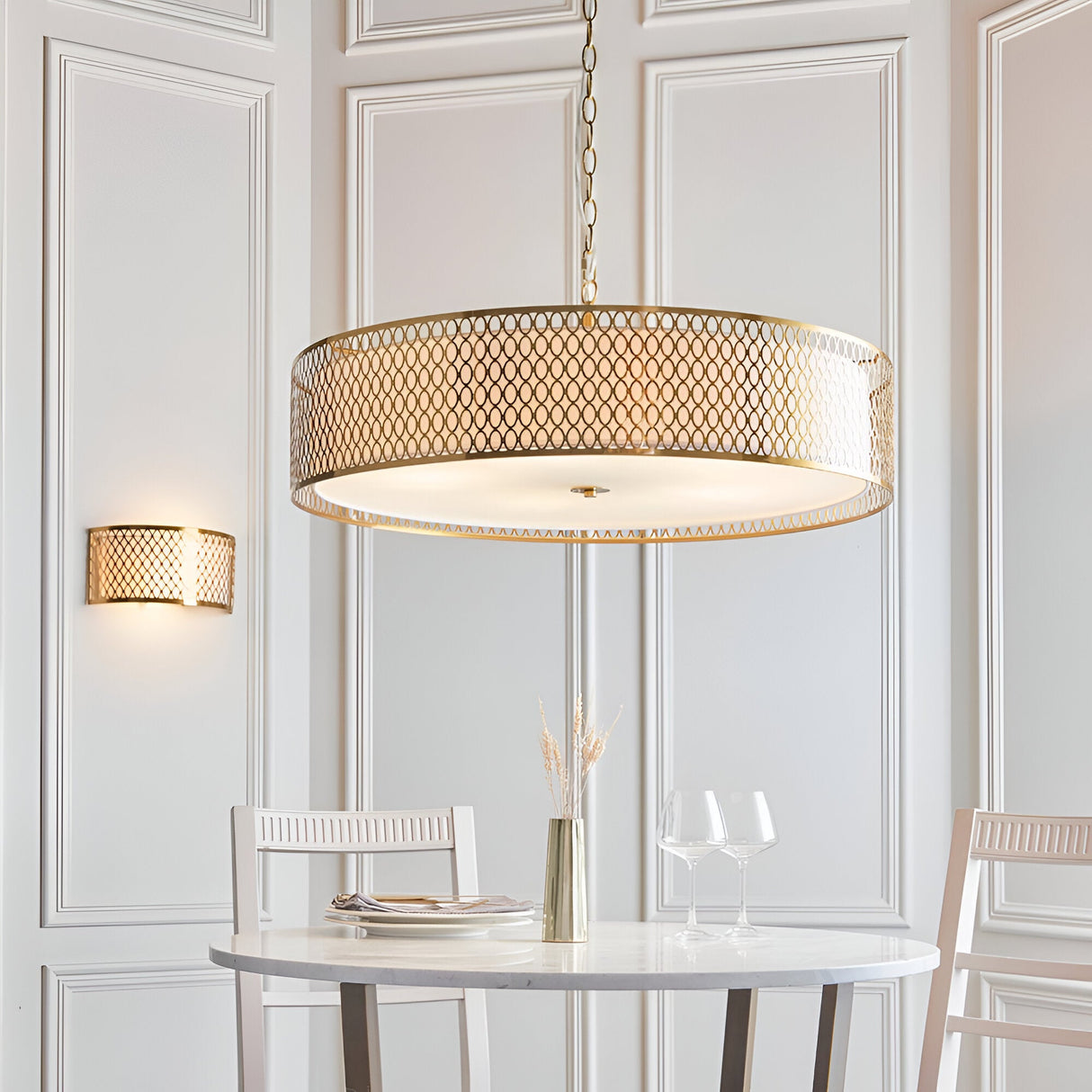 Rosaline 5-Light Pendant in gold and white with a large drum shade, geometric fretwork, white fabric inner, and frosted glass diffuser, above a dining table.