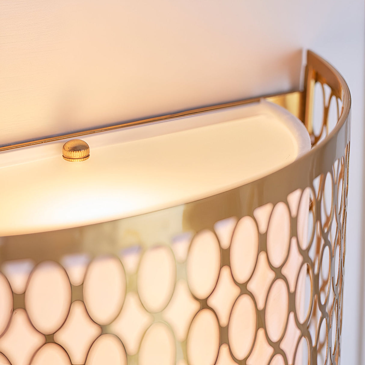 Close-up of the Rosaline 2 Light Wall Light in gold, showing curved geometric fretwork, white fabric inner shade, and frosted glass diffuser detail.