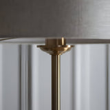 Close-up of the Brenley Floor Lamp in brass, showing the brushed metal stem and finial beneath a fabric shade with reflective inner lining.
