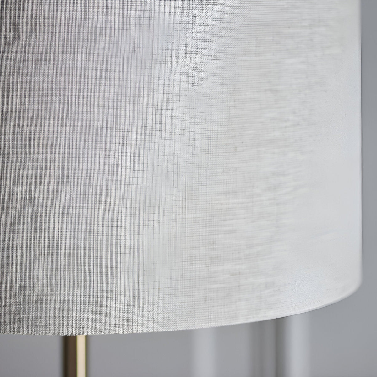 Close-up of the Brenley Floor Lamp in brass, showing the textured white fabric drum shade and slim brass leg on a plain background.