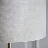 Close-up of the Brenley Floor Lamp in brass, showing the textured white fabric drum shade and slim brass leg on a plain background.