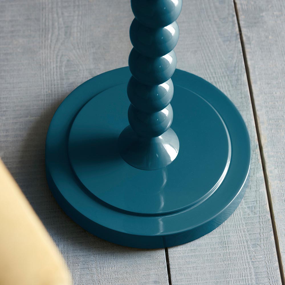 Close-up of the Endon Brenleigh floor lamp base in glossy marlin blue, showing stacked metal spheres on a round tiered base set on grey plank flooring.