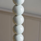 Close-up of the Endon Brenleigh Floor Lamp base in white, showing stacked glossy metal spheres against a pale panelled wall.