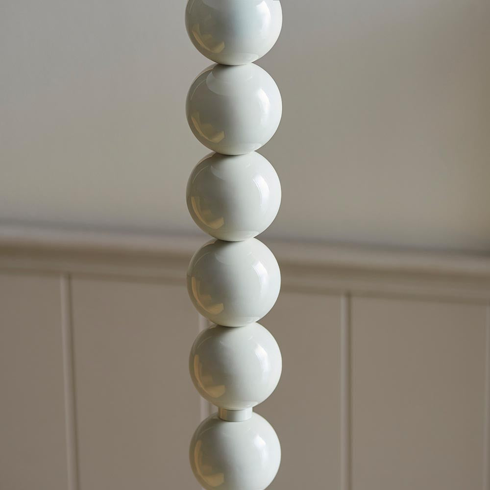 Endon Brenleigh Floor Lamp base in glossy almond white, showing stacked metal spheres against a neutral panelled wall.