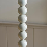 Endon Brenleigh Floor Lamp base in glossy almond white, showing stacked metal spheres against a neutral panelled wall.