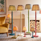 Endon Brenleigh table lamps with stacked sphere bases in blue, cream, green and pink, with patterned fabric shades, styled by a fireplace and armchair.