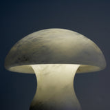 Morfia Mushroom Alabaster Table Lamp in soft white, close-up of the carved stone dome glowing from within against a dark background.