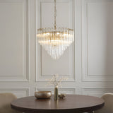 Cranshaw 12 Light Tiered Pendant in brass with clear ribbed glass rods, hung above a wooden dining table in a panelled room.