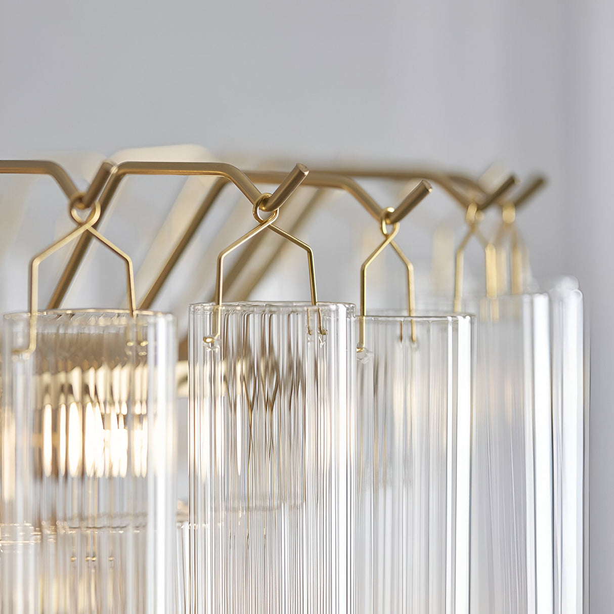 Close-up of the Cranshaw 12 Light Tiered Pendant in brass, showing clear ribbed glass rods hung from satin brass hooks and angled frame.