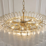 Cranshaw 12 Light Tiered Pendant in satin brass, with radiating arms and clear ribbed glass rods, suspended from a chain, shown against a light panelled wall.
