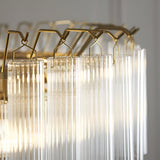 Close-up of Endon Cranshaw 12 light tiered pendant showing ribbed clear glass cylinders suspended from satin brass hooks on the frame.