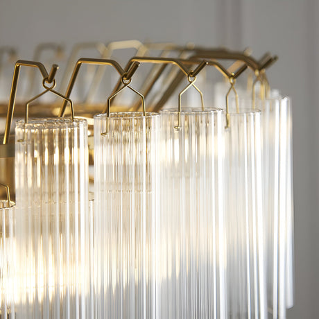 Close-up of Endon Cranshaw 12 light tiered pendant showing ribbed clear glass cylinders suspended from satin brass hooks on the frame.