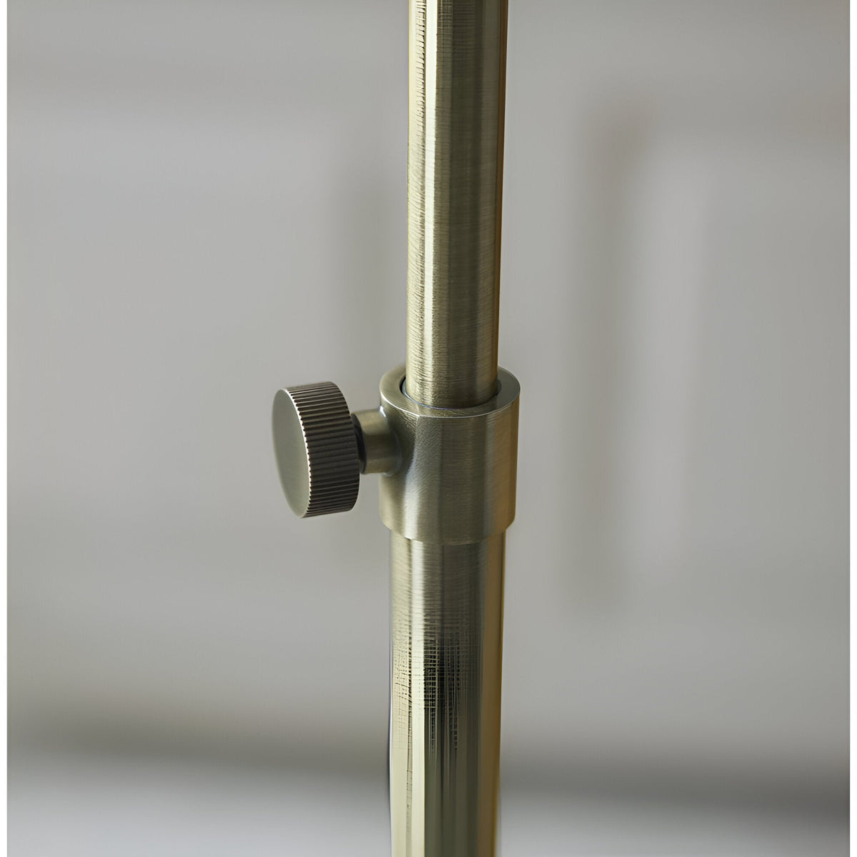 Close-up of the Endon Chartbourne floor lamp's antique brass stem with a knurled height-adjustment knob on the telescopic pole.
