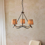 Endon Danemont 3 Light Pendant in black with a wave-shaped hoop and three hand-wrapped raffia tapered shades, hung from a chain against a plaster wall.