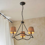 Endon Danemont 3 light pendant in black with a wave-shaped hoop carrying three tapered raffia shades, suspended by chain from a ceiling in a living space.