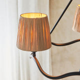 Close-up of a raffia tapered shade on the Endon Danemont 3 Light Pendant in black, showing the lit shade and curved matt black arm.