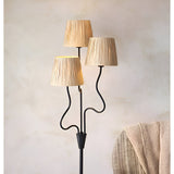 Endon Danemont 3 light floor lamp with wavy matt black arms and tapered hand-wrapped raffia shades, styled beside a woven basket in a neutral room.