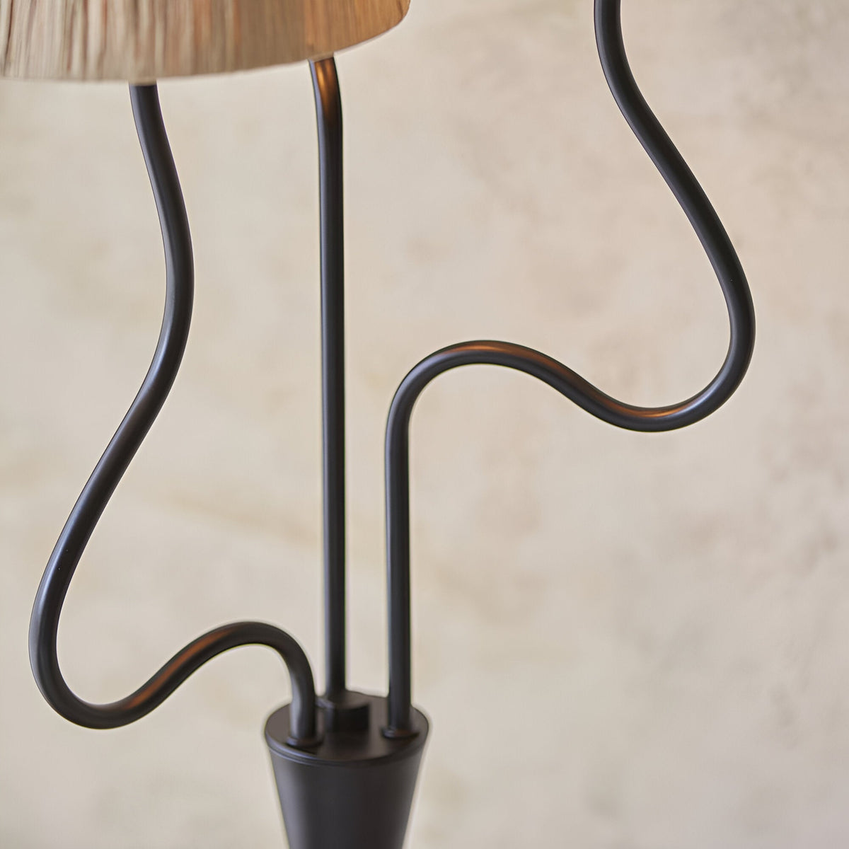 Close-up of the Endon Danemont 3 light floor lamp showing its matt black wriggle stem arms rising from a tapered base beneath a raffia shade.