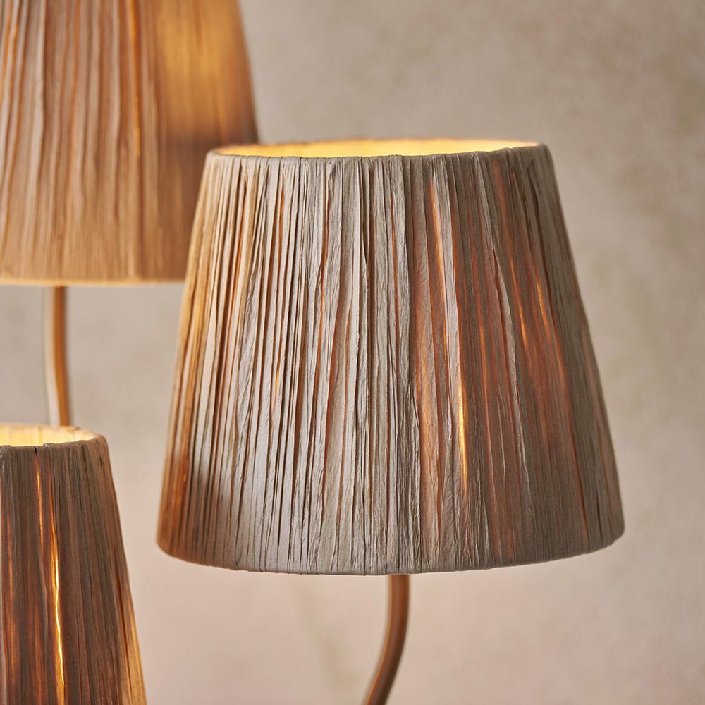 Danemont 3 Light Floor Lamp in aged brass, close-up of tapered raffia shades on brushed metal arms against a light background.