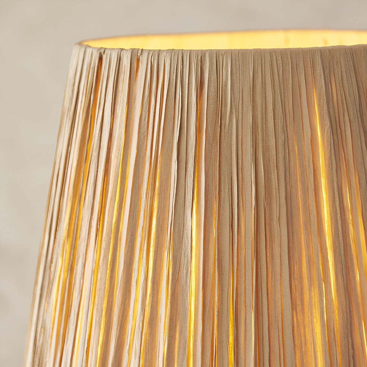 Close-up of the Endon Danemont Floor Lamp showing its hand-wrapped tapered raffia shade glowing warmly against a pale background.