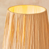 Close-up of the Endon Danemont table lamp showing its illuminated hand-wrapped natural raffia tapered shade against a neutral background.