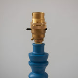 Close-up of the Endon Aldworth Ripple table lamp showing the brass B22 switched lampholder atop a satin blue turned wooden spindle base.