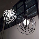 From the ceiling hang two spherical "Abstract 1 Light Pendants," representing modern pendant light design. The left pendant is adorned with white circular bands, while the right showcases black bands, both enclosing glowing bulbs. These abstract shapes are set against a backdrop of large windows and offer a dimmable feature for ambiance.
