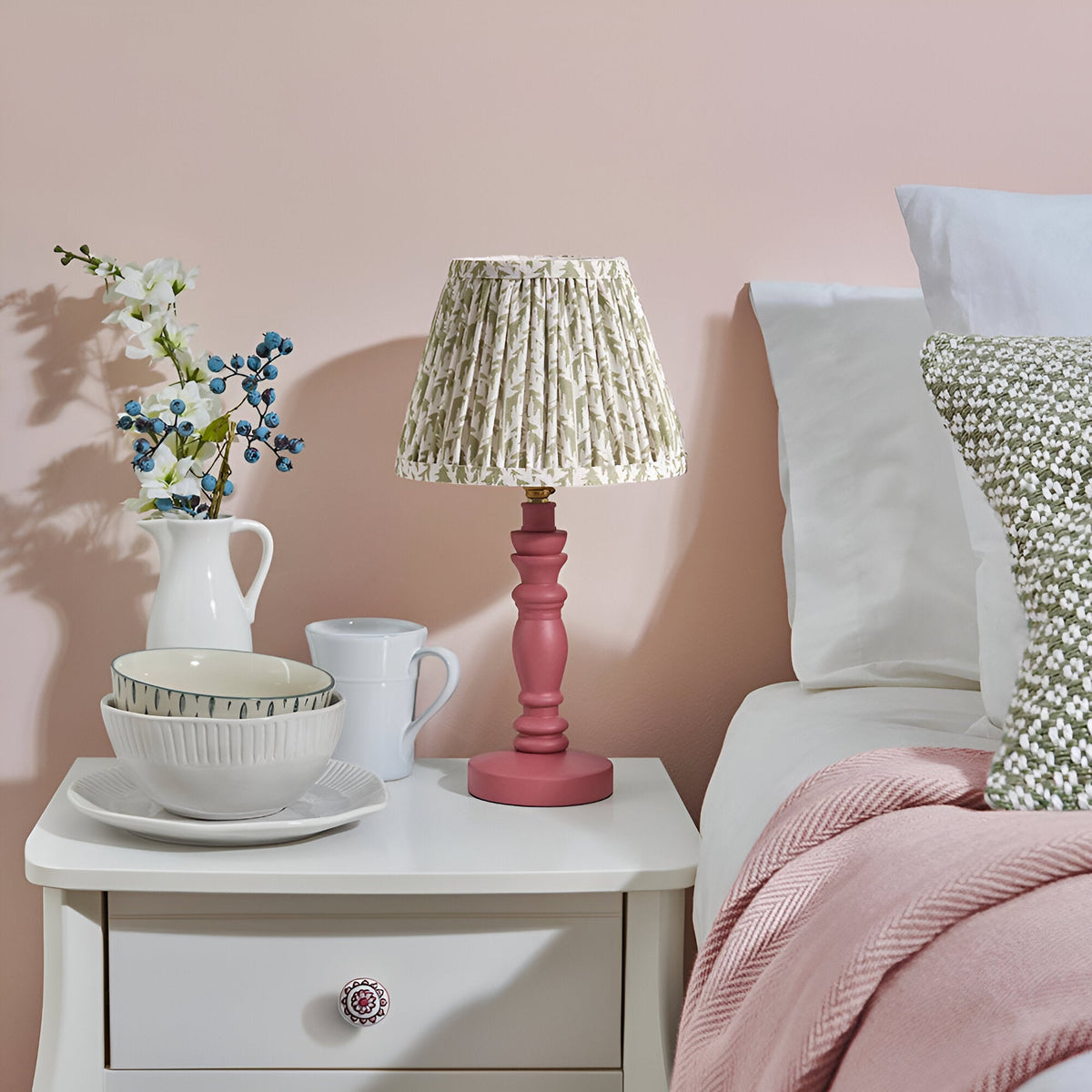 Endon Aldworth Leaf table lamp with pink clay turned spindle base and pleated green leaf-print shade on a white bedside table in a pink bedroom.