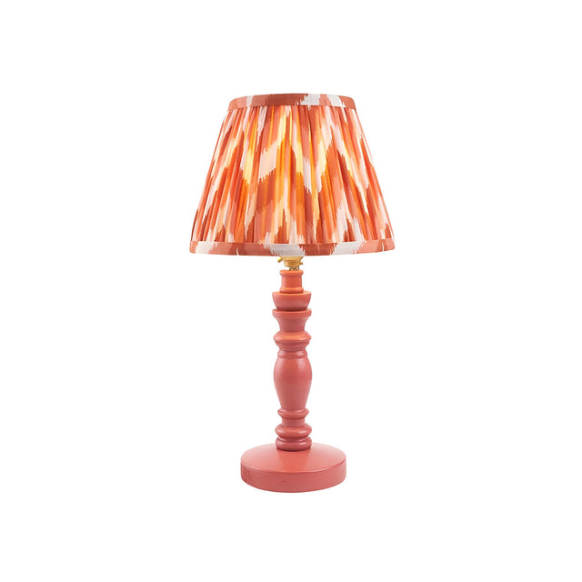 Aldworth Zigzag table lamp with a pink wooden spindle base and pleated orange zigzag-print fabric shade, brass B22 lamp holder, on a plain white background.