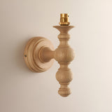 Endon Aldworth Leaf wall light with a turned natural ash spindle and brass B22 lampholder, mounted on a plain wall without its shade.