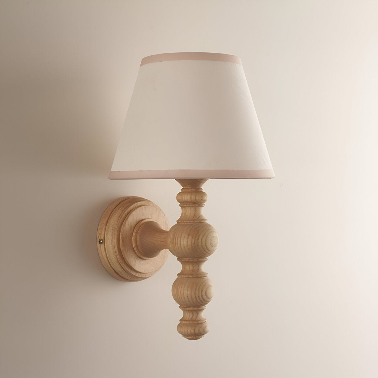 Aldworth Ivy Wall Light in natural turned ash wood with a tapered white fabric shade edged in pink, wall-mounted on a plain light background.