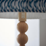 Close-up of the Endon Ashwood Floor Lamp showing stacked bamboo spheres, E27 holder switch, and marlin blue printed pleated shade edge.