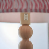Close-up of the Endon Ashwood floor lamp showing the cream E27 lamp holder with rocker switch above stacked natural bamboo spheres and pink pleated shade.