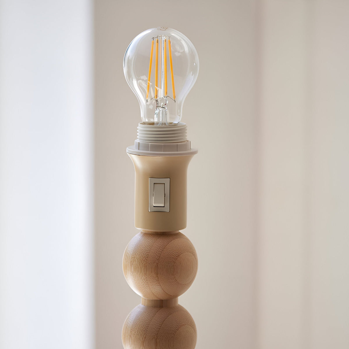 Endon Ashwood floor lamp detail showing an E27 filament bulb in a lamp holder with on/off switch above stacked natural bamboo wood spheres.