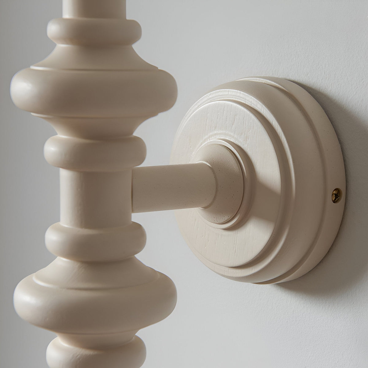Close-up of the Endon Bevbury Zigzag wall light's turned wooden spindle in satin almond white, mounted on a round backplate against a pale wall.