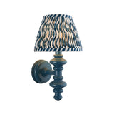 Endon Bevbury Ripple wall light with blue turned wooden spindle and tapered pleated shade in blue and cream ripple-print faux linen, on white.