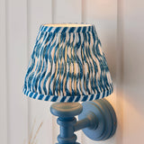 Endon Bevbury Ripple wall light with blue turned wooden spindle, brass B22 holder and tapered pleated shade in blue rippled faux linen print.