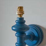 Close-up of the Endon Bevbury Ripple wall light showing the marlin blue turned wooden spindle, brass B22 lamp holder and matching blue circular wall plate.