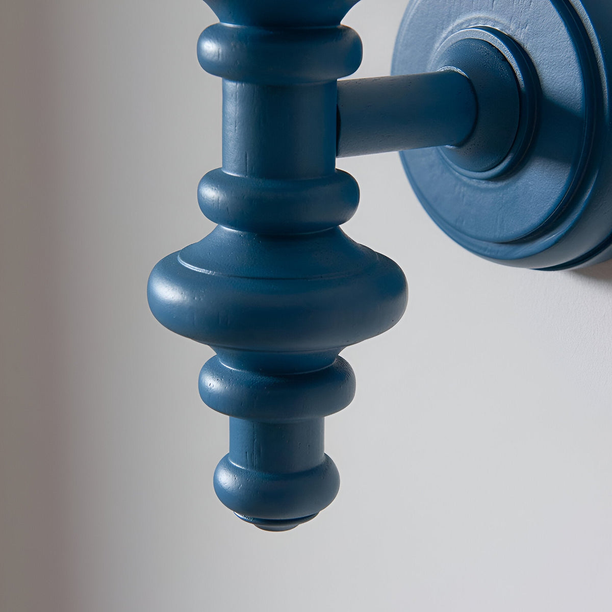 Close-up of the Endon Bevbury Ripple wall light's satin marlin blue turned wooden spindle and circular wall plate against a pale background.
